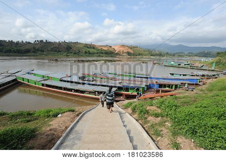 Hay Xai, Laos - 5 January 2012: tourists climbing on boats on river Mekong at Hay Xai, Laos