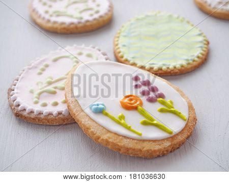 Easter sugar cookies with floral ornament. Homemade cookies glazed with royal icing. Ester treat upon rustic table. Beautiful biscuits in the shape of easter egg. Selective focus.
