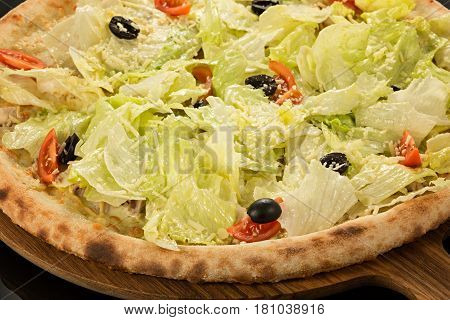 Caesar Pizza, Olive oil, mozzarella, chicken, iceberg lettuce, Caesar dressing, cherry tomatoes, olives and Parmesan on a black background