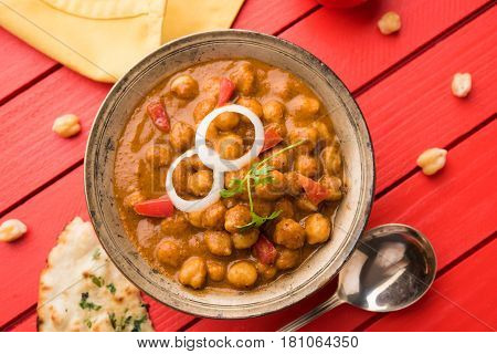 spicy chick peas curry or Chola Masala or Chana Masala or chole bhature or choley garnished with sliced onion and green coriander leaf, selective focus