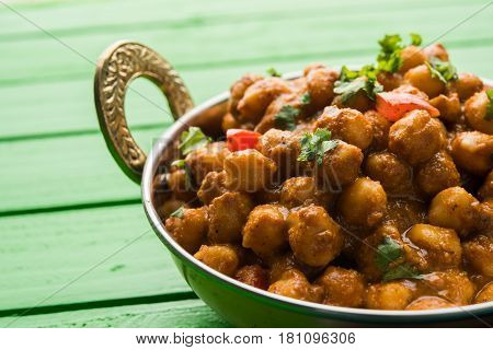 spicy chick peas curry or Chola Masala or Chana Masala or chole bhature or choley garnished with sliced onion and green coriander leaf, selective focus
