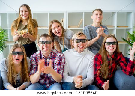 Friends in 3D glasses watching movie on sofa at home