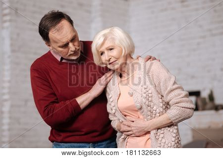 Bad sushi. Aged woman leaning and touching her tammy because of stomachache while her husband supporting her.