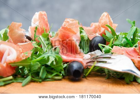 Chopping Board With Aragula And Raw Ham