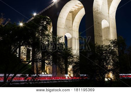 Night view of the arches of the Cabrillo bridge in San Diego, California, with car trails on the 163 freeway.
