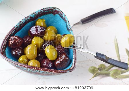 Green and black olives in olive oil in a traditional Greek bowl. Mediterranean lifestyle