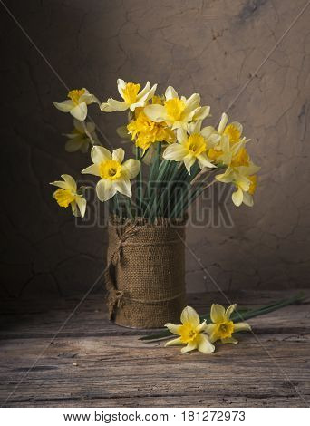 Amazing grunge background with Yellow flowers daffodils on turquoise texture. Beautiful Colorful Greeting Card for Mothers Day, Birthday, March 8. Top view, Flat lay. Horizontal Image With Copy Space