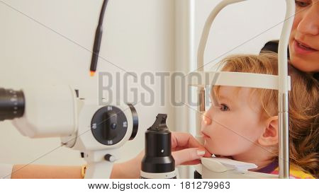 Child's optometry concept - little girl angry when checks eyesight in eye ophthalmological clinic, telephoto