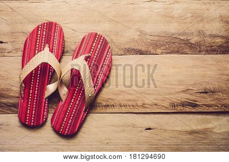 Red slipper on wooden for travel on sand in sea