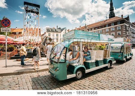 Riga, Latvia - July 2, 2016: Electric Car With Tourists People For Exploring City's Attractions Near Open Air Leisure Venue Recreation Center Egle In Sunny Day In Old Town On Kalku Street