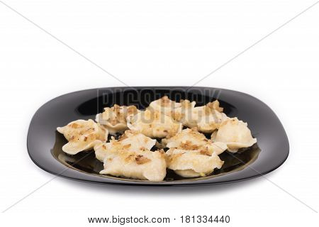 Fresh dumplings on a black plate seasoned with crispy onions.