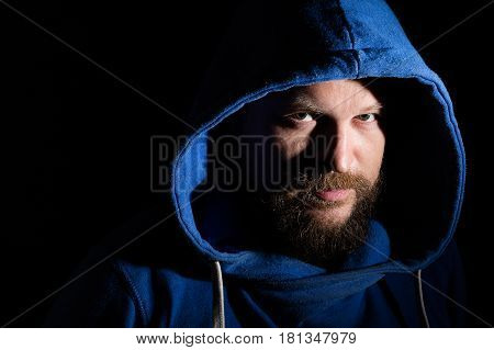 Solid bearded middle-aged man in a hood  portrait on black background