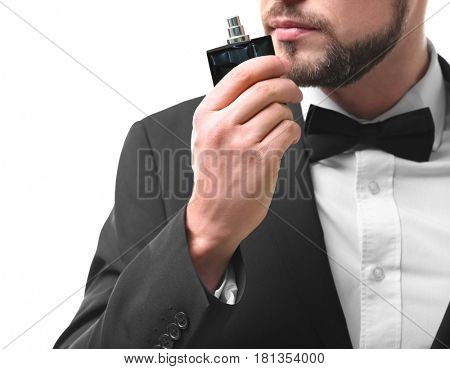 Handsome young man using perfume on white background
