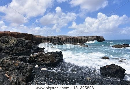 Waves crashing ashore on Aruba's black sand stone beach.