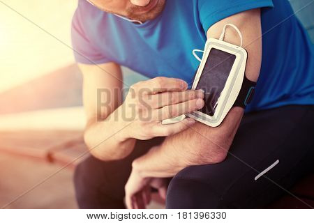 Athlete Listening Music And Touching Armband For Smartphone (intentional Sun Glare)