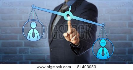 Male blue collar worker icon is outweighing a white collar employee symbol on a virtual pair of balances. Business concept for mediation pay gap performance review and workplace discrimination.