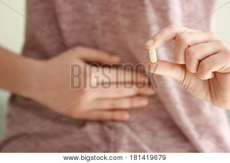 Young woman with pill suffering from pain in belly, closeup