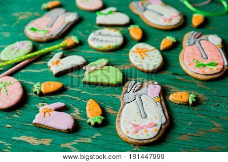 Easter gingerbread cookies in the shape of hares and carrots on a green background