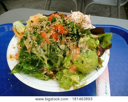 A Hawaiian style poki bowl on a blue tray outdoor dining