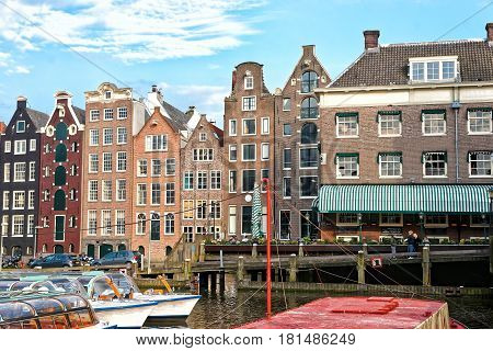 Amsterdam, Netherlands - May 2 2013:  Damrak with Canal boats and dancing houses in Amsterdam Netherlands. People on the background