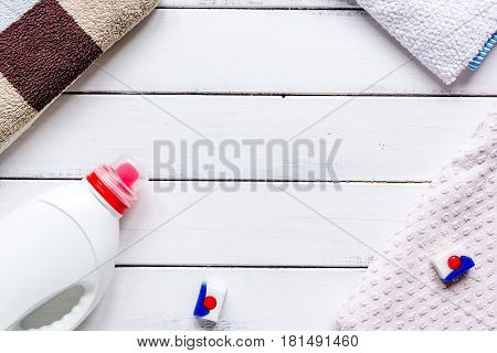 laundry set with pastel towels and detergent plastic bottel on white table background top view mockup