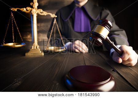 Law theme and concept. Mallet in the hand of judge in toga.
