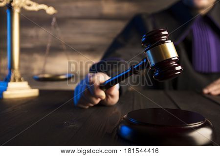Law theme and concept. Mallet in the hand of judge in toga.