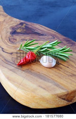 Herbs and spices on a wooden cutting board on a black abstract background