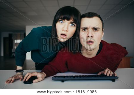 Young beautiful people puzzled look in the computer monitor. Very emotional look at the camera