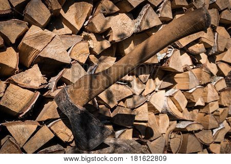 Old axe in log on a firewood background.