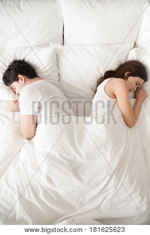 Tired of disagreements, unhappy indifferent couple falling asleep back to back in bed at home. Boyfriend and girlfriend sleeping separately, having conflict and ignoring each other, sexual problems