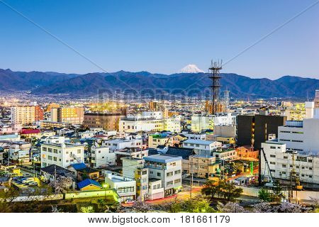 Kofu, Japan city skyline with Mt. Fuji peaking over the mountains.