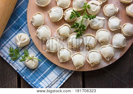 Dumplings raw on a round board. Russian national food. The process of cooking dumplings.