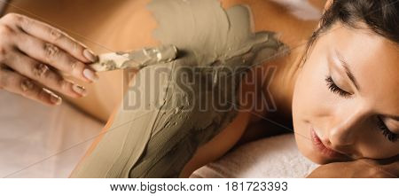 The girl enjoys mud body mask in a spa salon.  Luxury treatment.