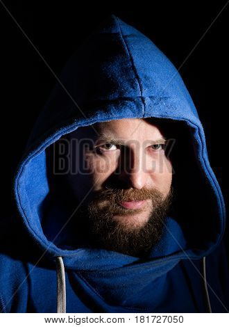 Solid bearded middle-aged man in a hood  portrait on black background