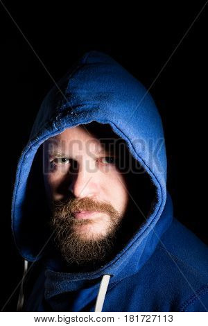 Solid bearded middle-aged man in a hood  portrait on black background