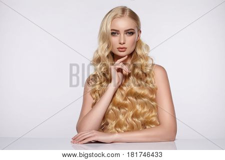 Beauty portrait of an attractive girl with long curly hair at the table.