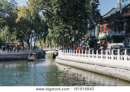 25 October 2014 -In Beijing ShiChaHai. Boats and bridge on Qianhai lake in Shichahai lake of Beijing China many tourists walking on side