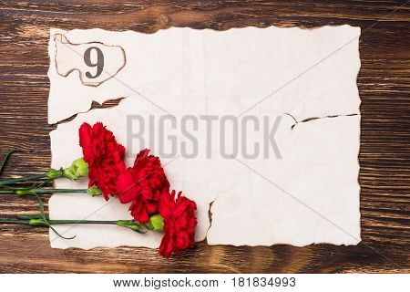 three red carnations on the sheet of old paper concept