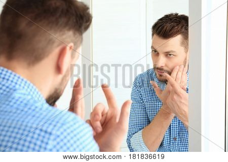 Young man putting contact lenses in front of mirror at home