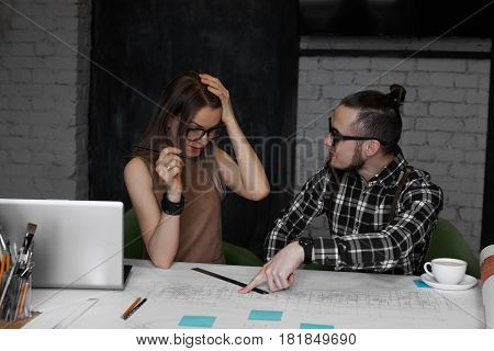 Young talented male explain mistakes in engineer drawings. Student girl do not pass exam and have bad mood. Teacher giving advice during practicing lesson in university. Correction work.