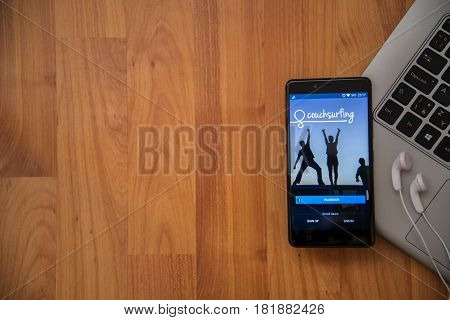 Los Angeles, USA, april 16, 2017: Couchsurfing application on smartphone with earphones and notebook on wooden background.