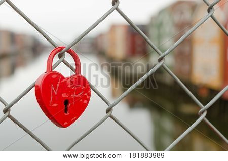 A red padlock is fastened in the fence on the bridge Gamle Bybro in Trondheim