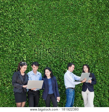 Businesswoman and businessman working outside office using laptop computer mobile phone and tablet device at green leaf wallmobile office conceptcopy space for adding text or designSquare banner.