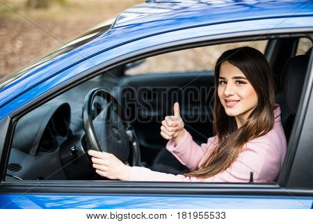 Young Woman Doing Thumps-up In Car. Woman Drive Car