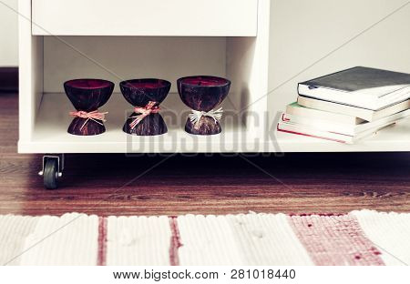 White Nightstand With Candles And Books, Next To A Multi-colored Rug