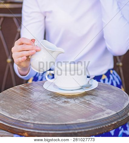 Coffee Always Better With Milk. Hand Female Adding Milk To Black Coffee Outdoors Cafe Terrace, Close