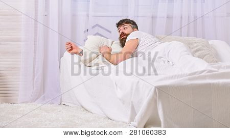 Man In Shirt Laying On Bed Awake, White Curtain On Background. Wake Up And Oversleep Concept. Macho 