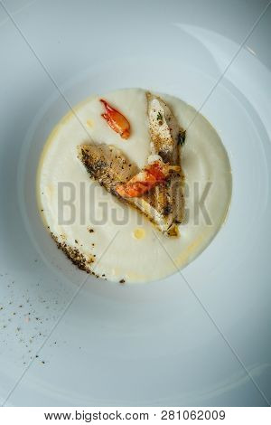 Closeup Fish Cream Soup Decorated With Fried Pieces Of Fish, Prawn, And Spices
