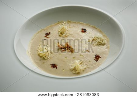 Closeup Beige Seafood Cream Soup Decorated With Dried Squid And Soy Sauce